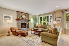 Spacious living room with fireplace, carpet floor and rug. There are two green sofas and leather brown armchair